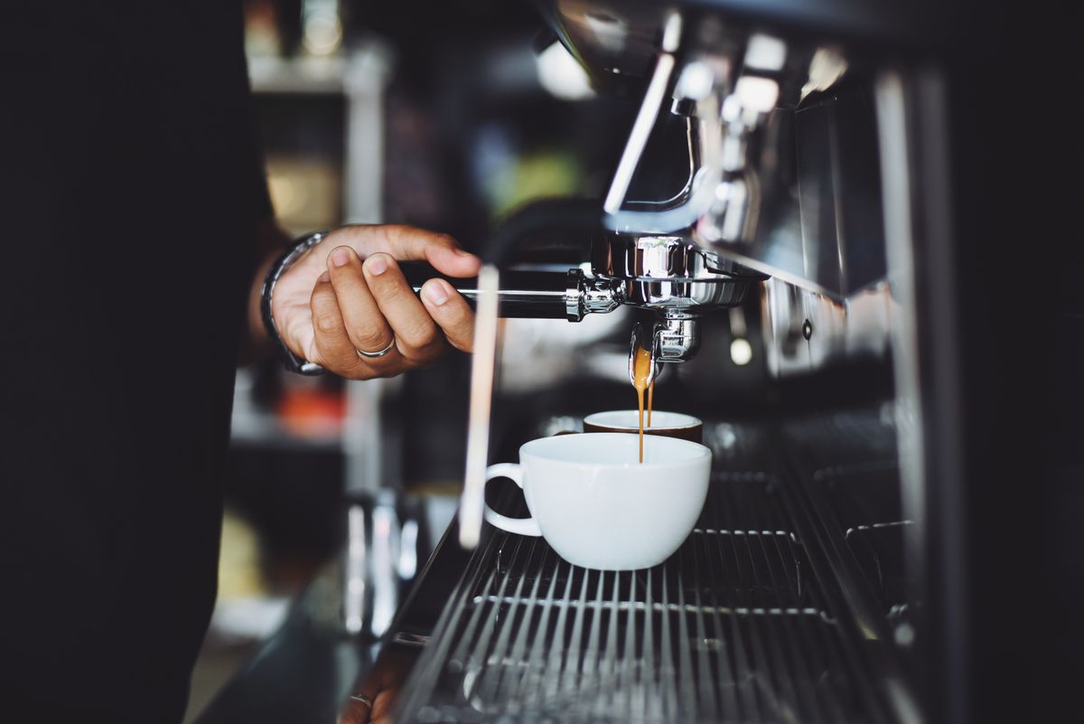 Barista operando el portafiltro de una máquina de espresso profesional en una cafetería